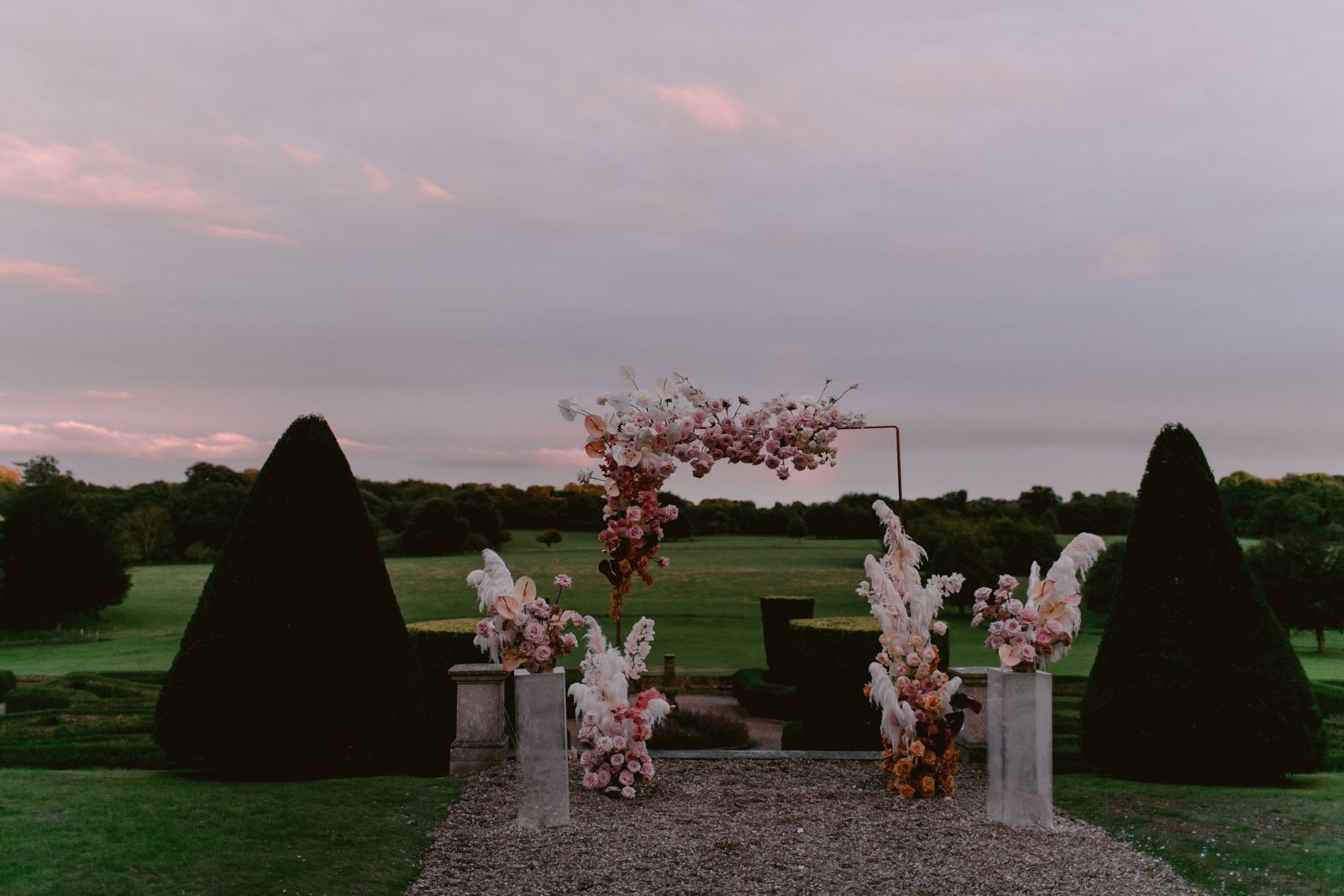 Wedding arch decorated with flowers and feathers on a pathway