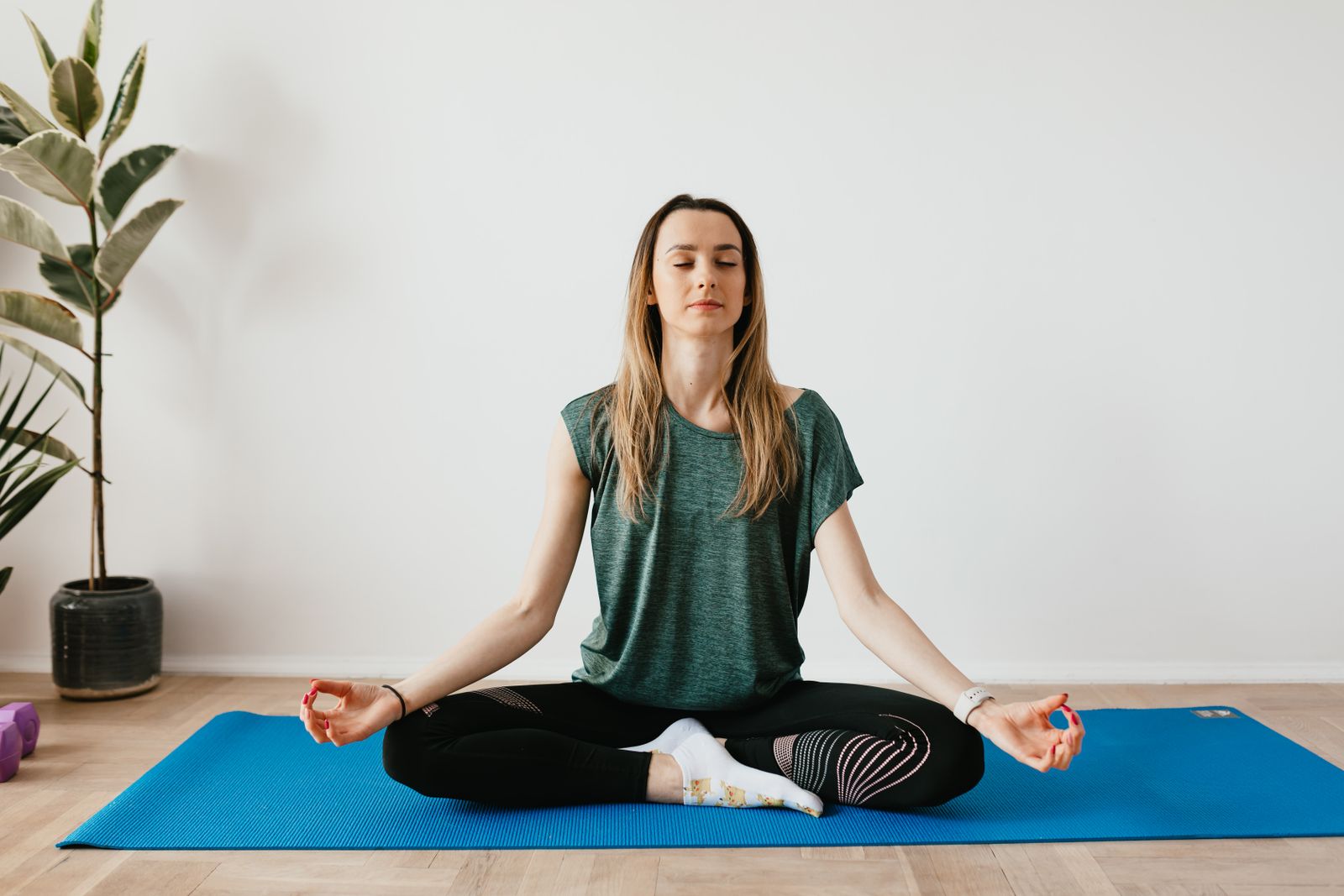 Woman meditating in padmasana pose on a mat